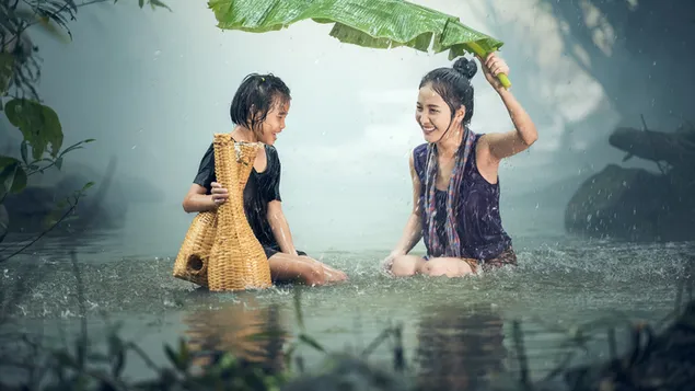 Niño y mujer joven divirtiéndose en el río en un día lluvioso en el bosque