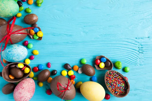 色付きの卵とカラフルなキャンディーとイースターの日のチョコレートの卵 2K 壁紙