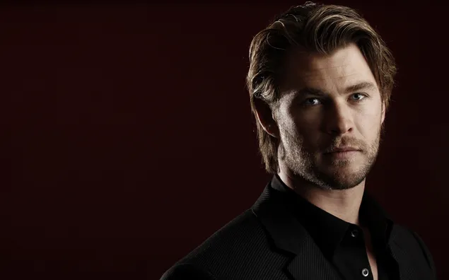 Chris Hemsworth čeden igralec v črni obleki in temno rdečem ozadju 2K ozadje