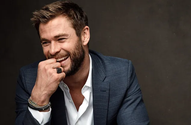 Chris Hemsworth, aktor tampan berjas biru dengan kemeja putih, tertawa 2K wallpaper