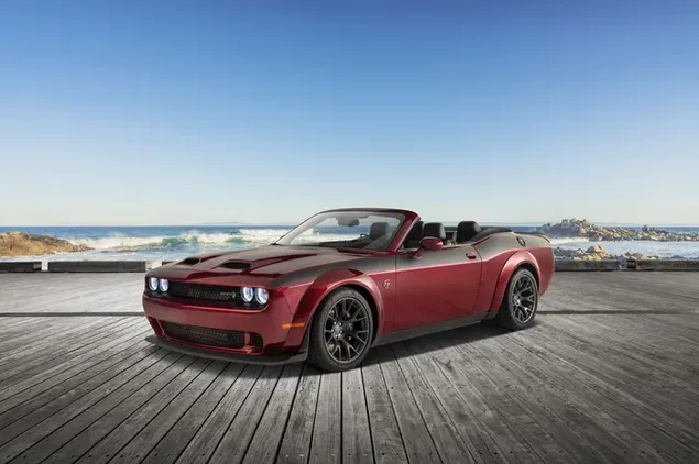 Coche deportivo convertible de color rojo Dodge Challenger SRT estacionado en un piso de madera al aire libre junto al mar