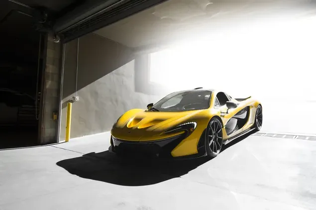 Coche deportivo Mclaren de color amarillo y negro y ruedas de acero con su maravilloso diseño está estacionado en un garaje cerrado