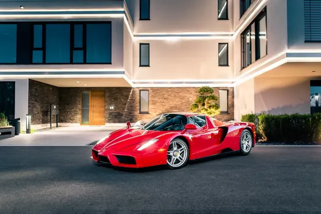 Coche deportivo rojo maravilla Ferrari estacionado en la carretera asfaltada frente al edificio descargar