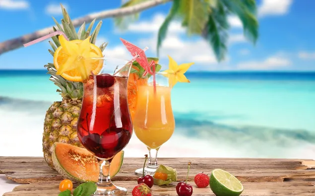 Cóctel de piña, limón, naranja, cereza y lima de frutas de verano en una mesa de madera con vistas al mar y a las nubes