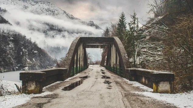 Camino de puente de hormigón entre montañas nevadas