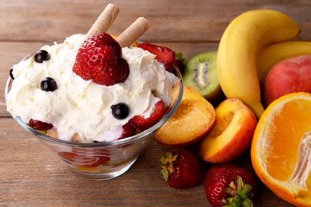 Kremna sadna solata v skodelici iz prozornega stekla, postavljena na leseno mizo 4K ozadje