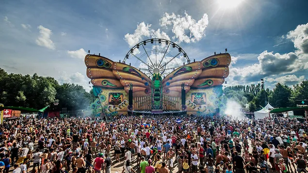 Multitud bailando en la plaza nublada y divertida del festival de música Tomorrowland 4K fondo de pantalla