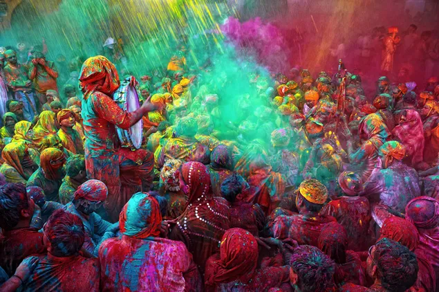 Een menigte mensen spettert en geniet van de kleur van Holi download