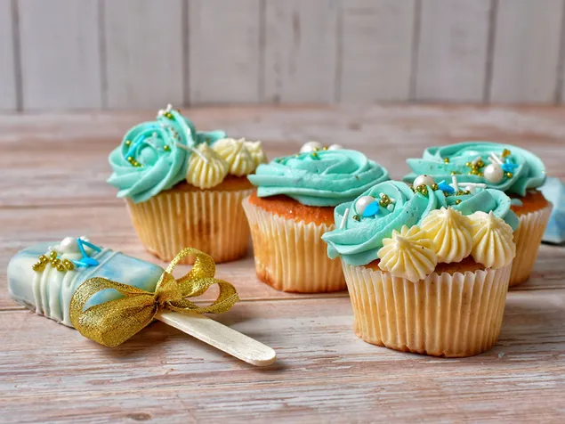 Kolački, okrašeni s sladoledom in modro obarvanimi sladicami na lesenih tleh HD ozadje