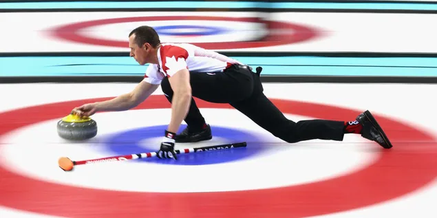 Curlingspeler die granietsteen naar doel op ijsbaan probeert te sturen