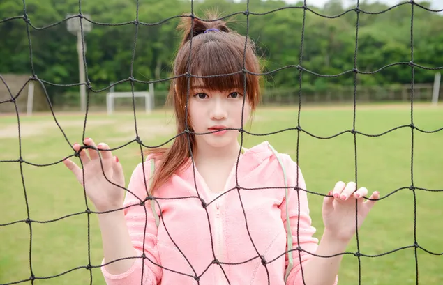 Leuk Aziatisch meisje met roze jas op het veld