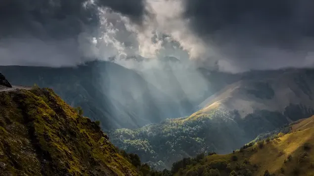 La luz del día golpea bosques y colinas a través de nubes oscuras