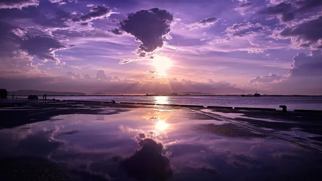 Die Landschaft, die wie zwei separate Fotos aussieht, mit der Reflexion der aufgehenden Sonne mit dunklen Wolken im Wasser