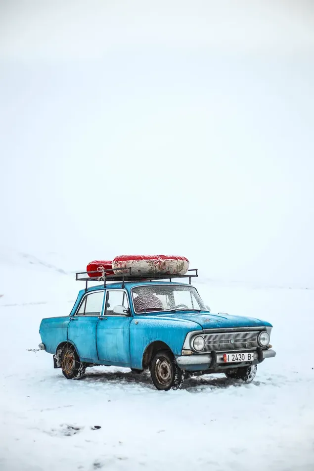 冬に雪が降った地面に荷物を載せた小さな青い車 ダウンロード