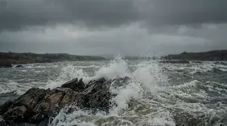 dramatic waves crash on rocks under stormy skies download
