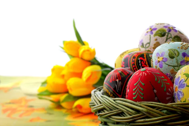 Ostern ästhetisch bemalte Eier in einem Korb und einem Bündel gelber Tulpen 8K Hintergrundbild