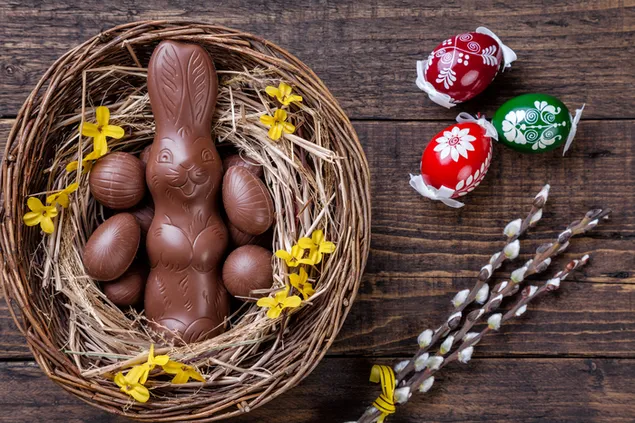 Osterei und Hasenschokolade in einem Korb und 3 bemalten Eiern 4K Hintergrundbild