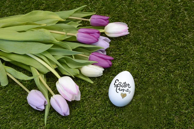 Huevo de Pascua con tulipanes morados y blancos en tiempo de Pascua