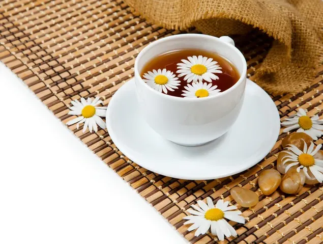 Een kopje thee in een bruine placemat met bruin tafelkleed en bloemen