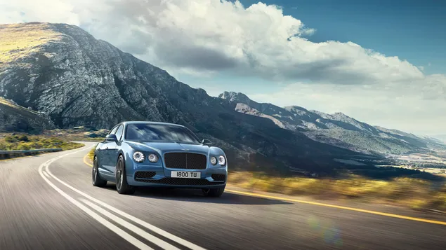 Ein Bentley-Sportwagen, der mit seinem Design auf der Asphaltstraße zwischen den Hügeln fasziniert, die so hoch sind, dass sie die Wolken berühren