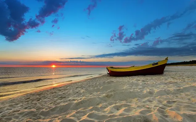 Ein kleines Boot am Strand in der Landschaft, wo die roten Sonnenstrahlen herunterladen