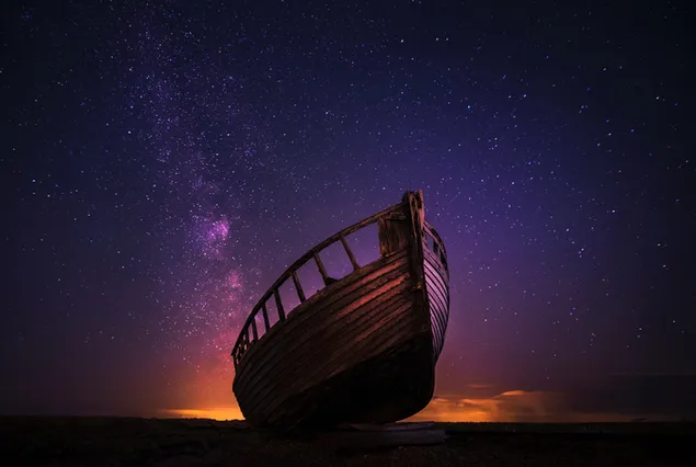 Ein verlassenes altes Holzschiff unter der Schönheit der Sterne, die in der dunkelsten Stunde der Nacht auftauchen