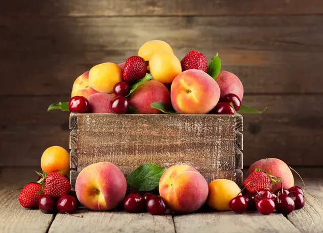 Eine Holzkiste voller süßer Äpfel, Pfirsiche, Aprikosen und Kirschen