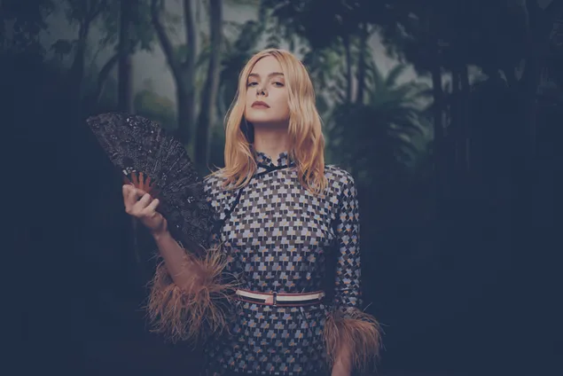 Elle Fanning holding a fan with a forest wallpaper
