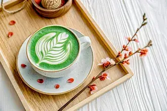 Disfrutando de un delicioso té verde con leche y un hermoso arte latte en una bandeja de madera 4K fondo de pantalla