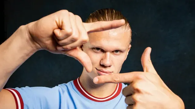 Erling Haaland gestikulerar med en Manchester City-tröja framför en svart bakgrund ladda ner