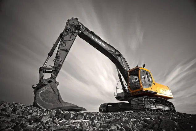 Excavadora en el sitio de construcción con color amarillo sobre fondo nublado blanco y negro descargar