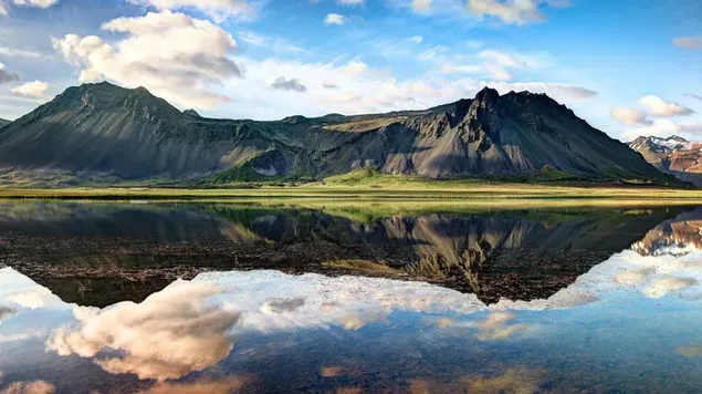 Fascinante vista del clima nublado y colinas rocosas reflejadas en el lago
