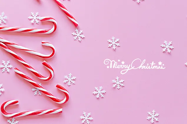 Felices saludos navideños en fondo rosa con bastón de caramelo y copos de nieve