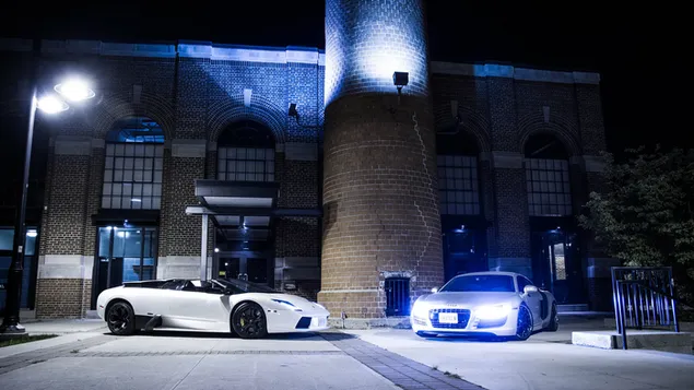 Ferrari blanco y R8 estacionados frente al edificio durante la noche descargar