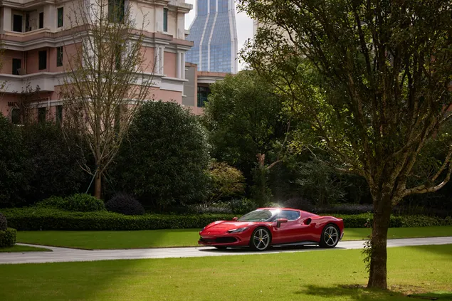 Ferrari rojo 296 gtb al lado del árbol y la hierba detrás del edificio