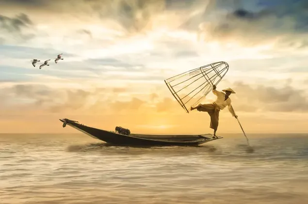 Muat turun Lelaki nelayan di laut yang tenang dan pemandangan langit keemasan