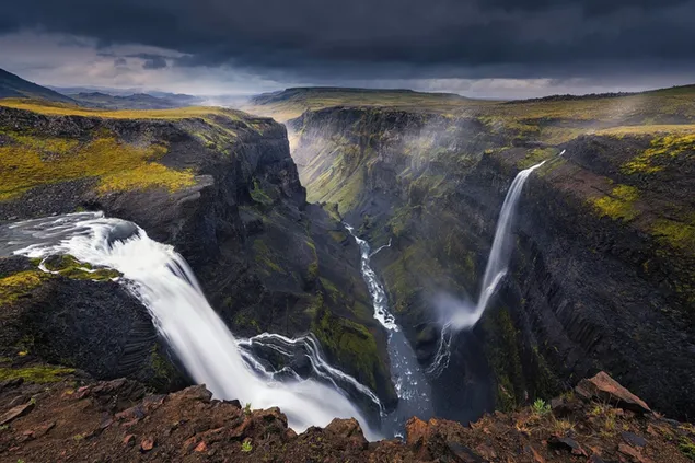 アイスランドの壮大な自然の中でユニークな景色を望む流れる滝