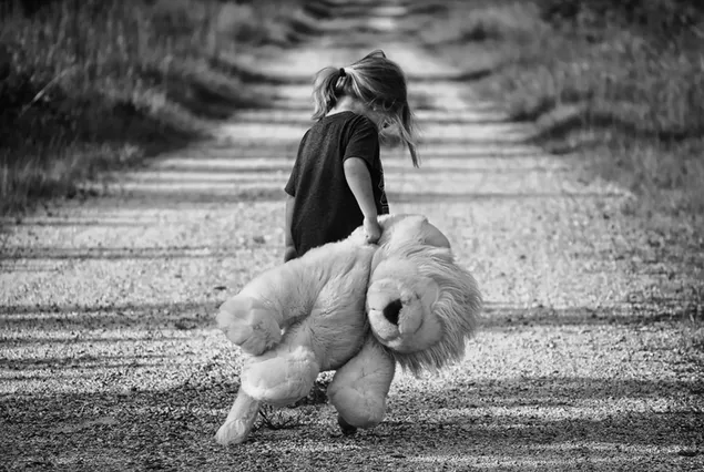 Foto hitam putih gadis dan boneka beruang berjalan di jalan tanah yang dikelilingi oleh rumput unduhan
