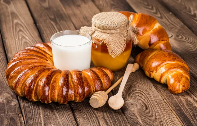 Viennoiserie Prancis dengan susu dan madu di meja kayu 4K wallpaper