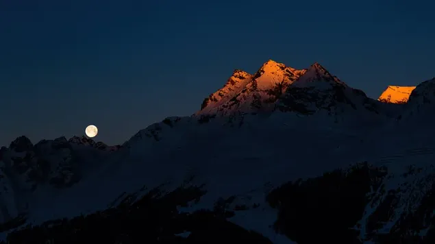 Full moon behind snowy mountains