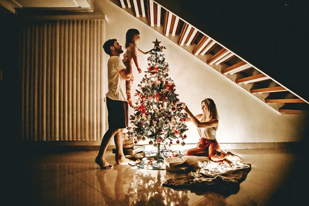Gelukkige familie die de kerstboom voorbereidt en decoreert