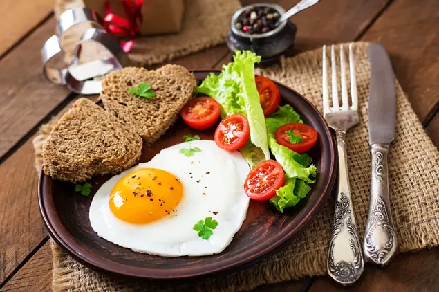 Gezond ontbijt van tarwebrood, eieren met de zonnige kant naar boven en groenten