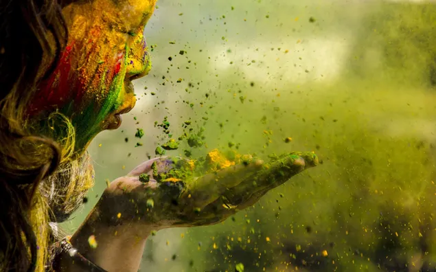 Taustakuva Tyttö puhaltaa Holi-värejä 2K