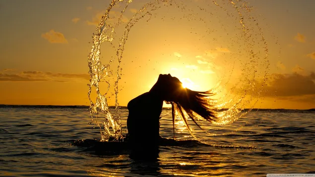 Gadis bermain dengan air di laut saat matahari terbenam