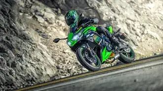 zelena kawasaki motorka a motorkar s helmou na asfaltove silnici vedle skaly a hliny stahnout