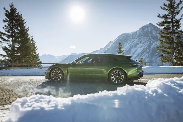 Porsche taycan turbo S (2022) hijau di atas salju aspal di pinggir jalan matahari di langit unduhan