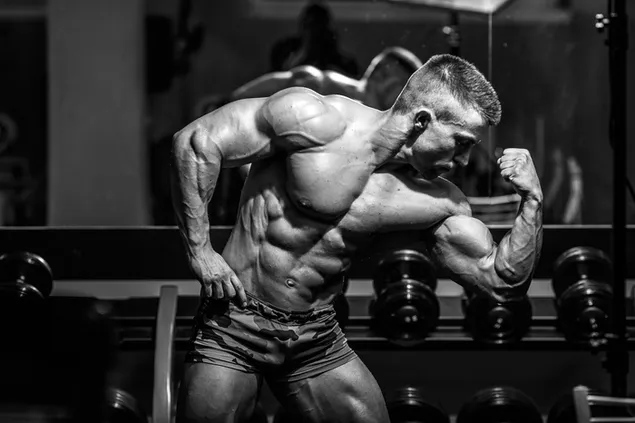 Sportschool bodybuilder pronkt met zijn spieren zwart-wit foto download