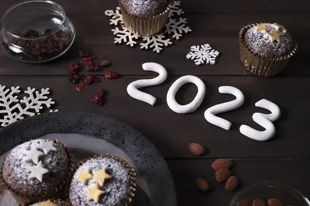Selamat tahun baru 2023 kue dan cokelat disiapkan di atas meja kayu untuk perayaan tahun baru
