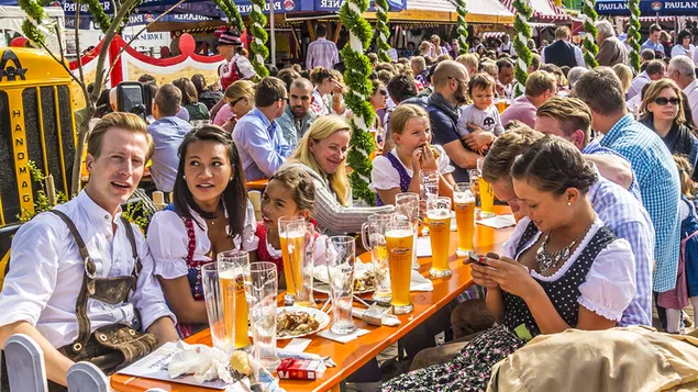Gelukkige vroue en gelukkige mans drink bier aan tafel by Duitsland Oktoberfest-viering aflaai