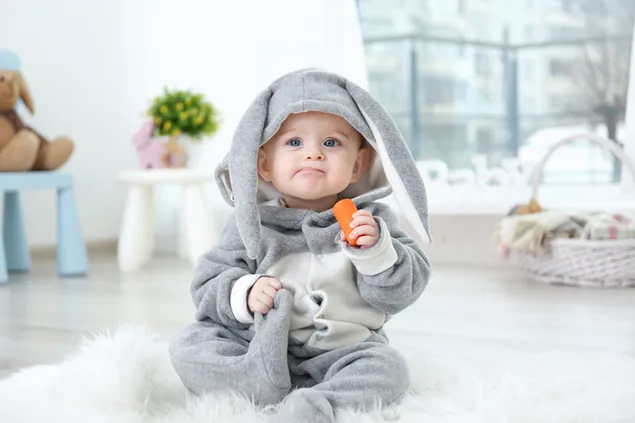 Häschenkostüm niedliches Baby, das Karotte isst